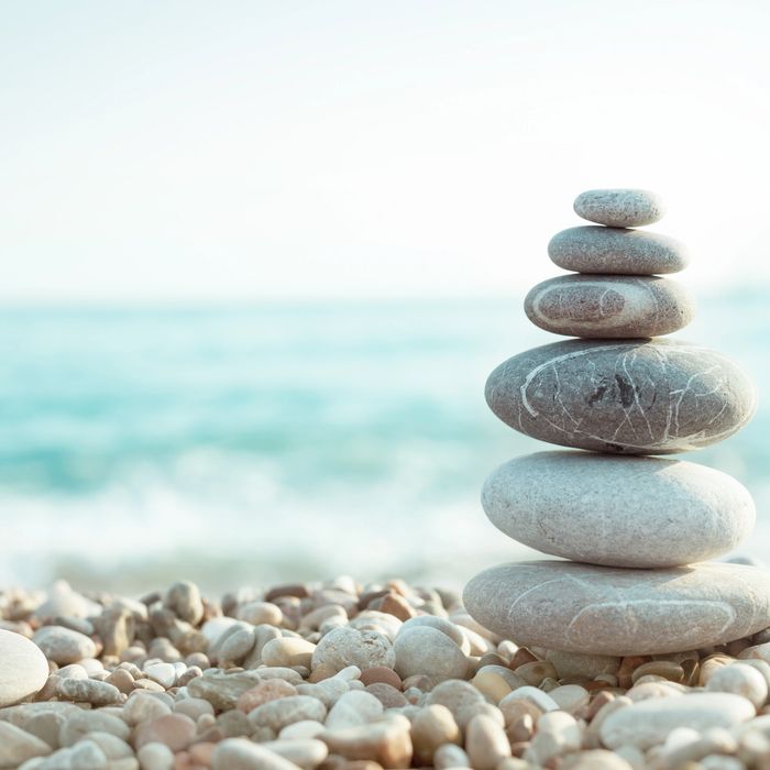 Stacked smooth stones on a pebble beach with a calm sea background.