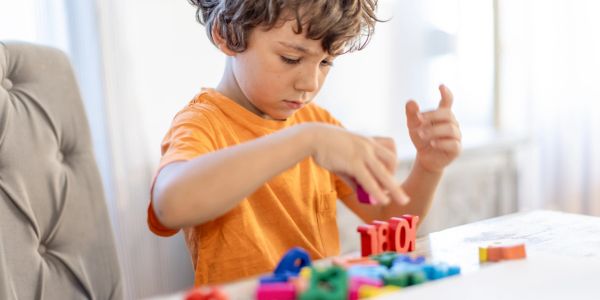 Young boy focused on building with colorful blocks.