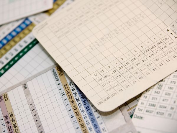 Close-up of golf scorecards scattered on a surface.
