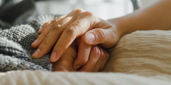 Close-up of two hands holding each other gently, symbolizing care and support.
