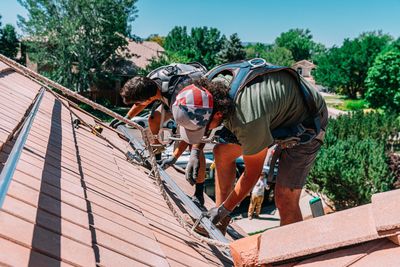 Two workers installing solar panels on a roof.