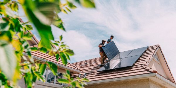 Workers installing solar panels on a sunny roof.