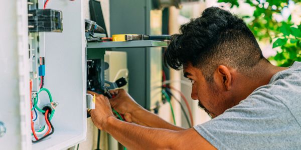 Technician working on electrical wiring outdoors.
