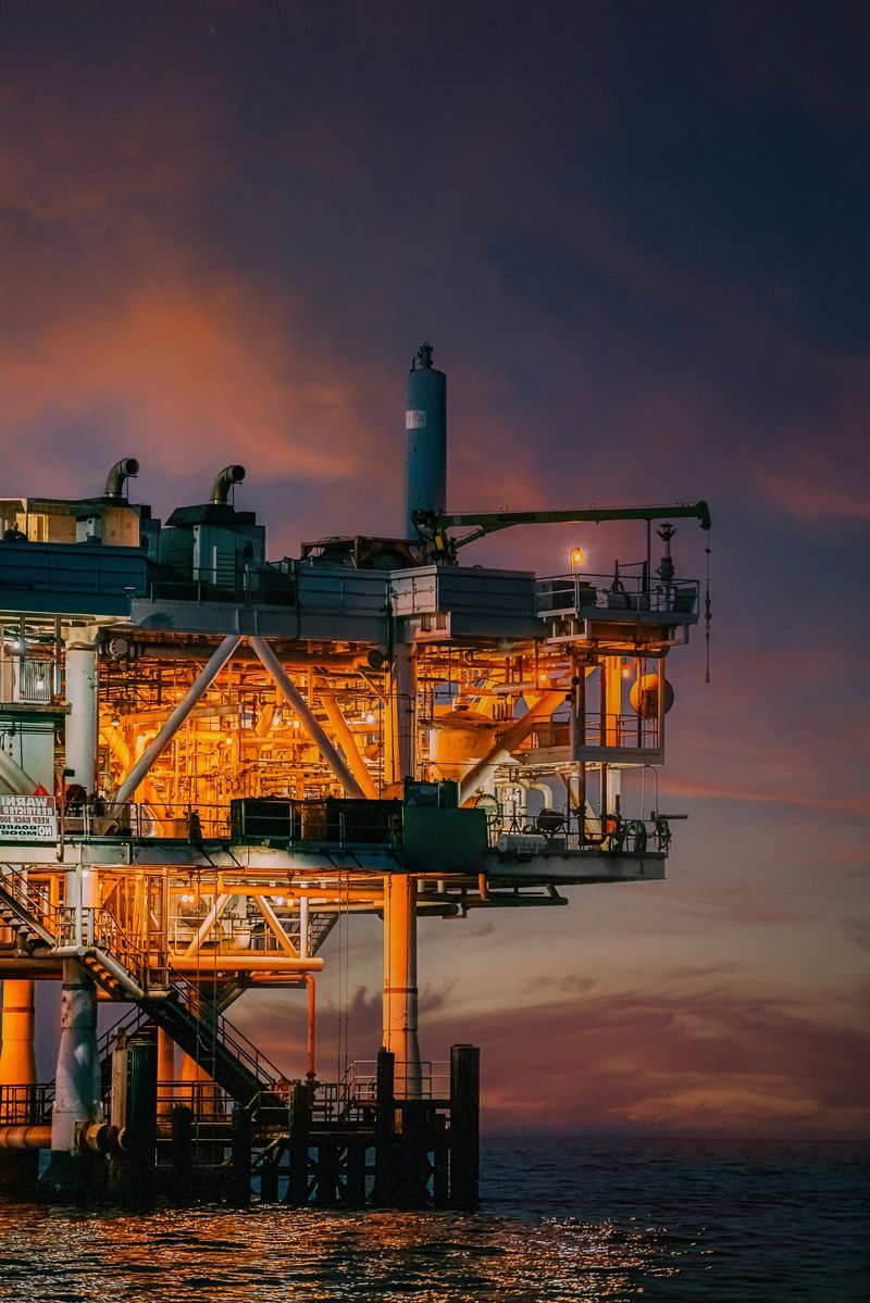 Offshore oil drilling during sunset in Huntington Beach, California. The pink sunset tones highlight the machines used for extracting fossil fuels like crude oil and natural gas. 

This image depicts where the energy industry meets the Pacific Ocean's natural beauty, bringing up discussions about fuel, power, energy challenges, and environmental issues tied to oil and gas.
