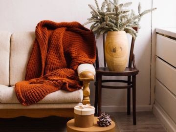 Cozy scene with orange blanket, chair, and wooden decor.
