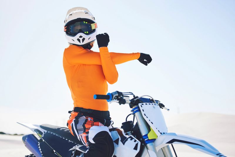 Motorbike, arm stretch and ready for race in desert, training and practice for challenge on sand dunes. Athlete, fast and adrenaline in extreme sports, fitness and energy for competition on dirt bike