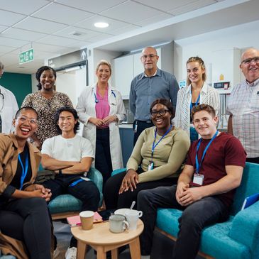 Diverse group of healthcare professionals and trainees smiling in a hospital break room.