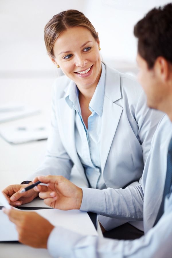 Two professionals discussing work with smiles in an office setting.