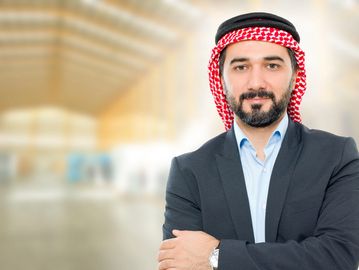 Confident man in traditional Middle Eastern attire with business suit.