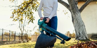 Person using a leaf blower in autumn.