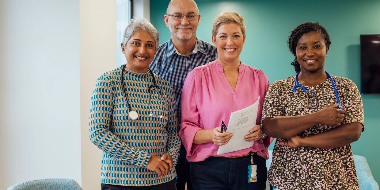 Four diverse healthcare professionals smiling together in a medical office.