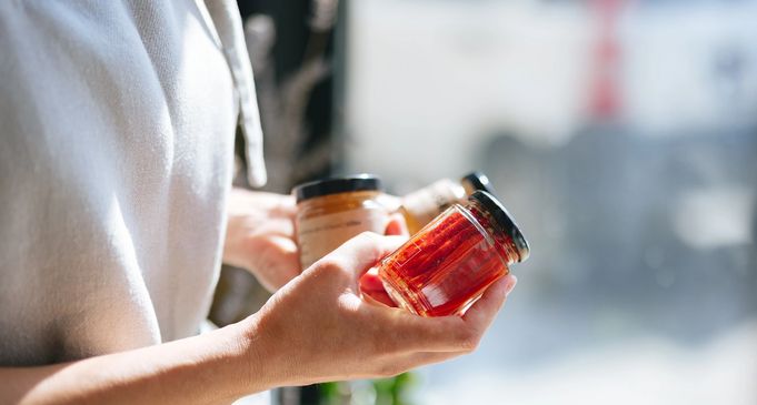 Jars filled with homemade red jam or preserves on a wooden table.