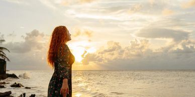 Woman standing by the ocean during sunset, enjoying the view.