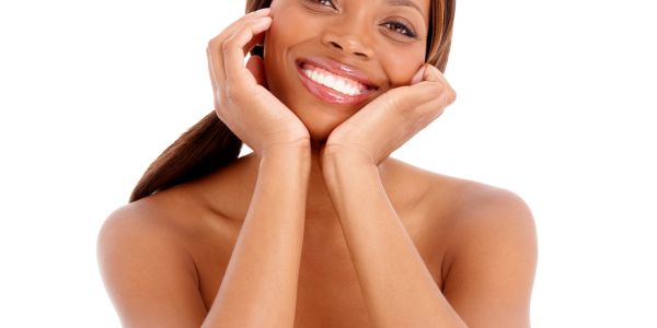 Smiling woman with radiant skin posing with hands on her cheeks.