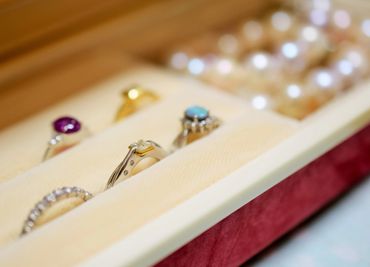 Close-up of rings and pearl earrings in a jewelry box.