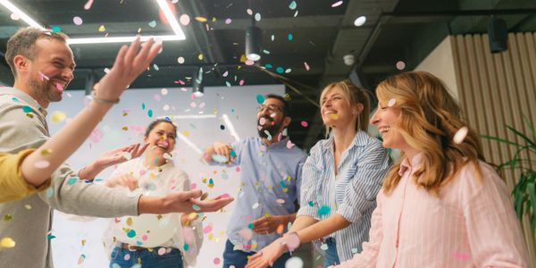 Colleagues joyfully celebrating with confetti in an office setting.