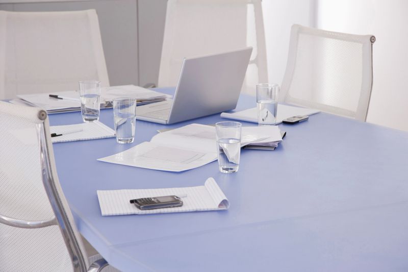 Laptop and documents on table in conference room