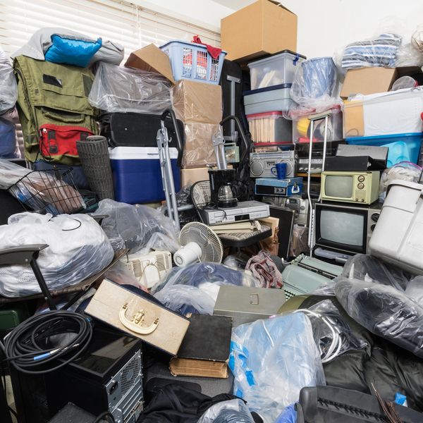 A disorganized room with heaps of bins boxes reflecting significant clutter.
