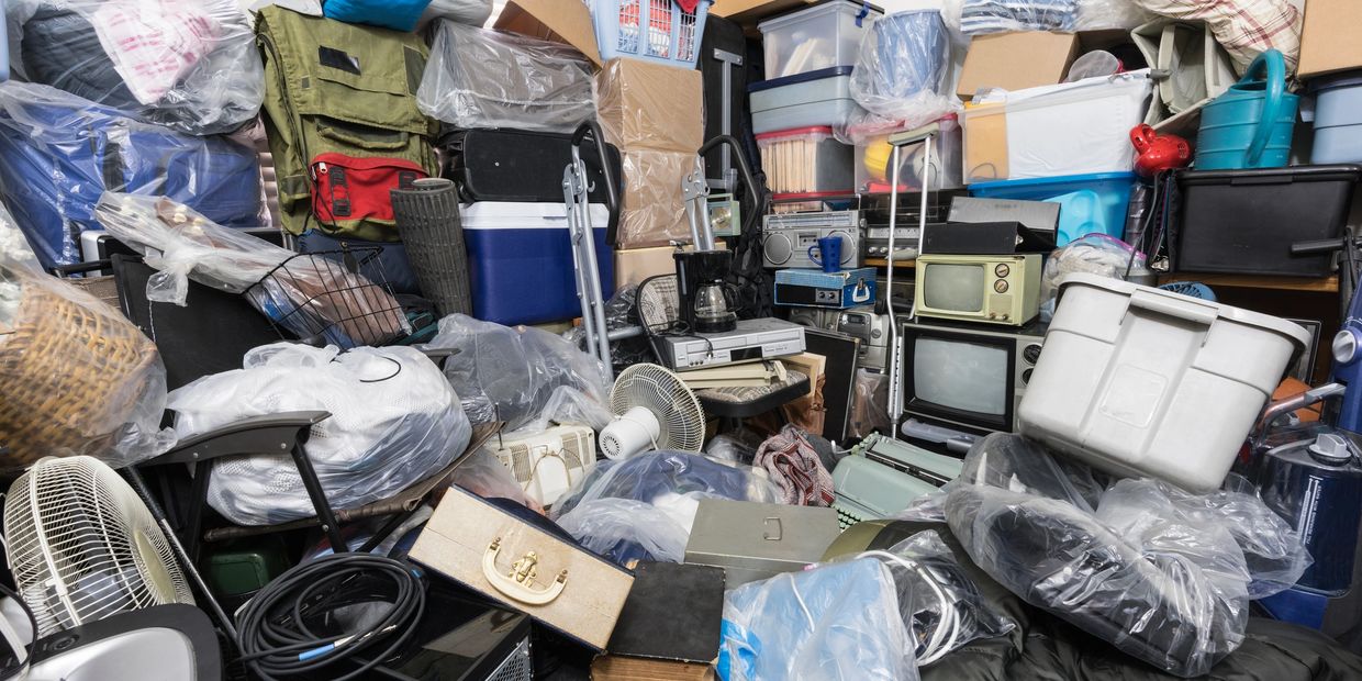 A cluttered storage room filled with boxes, electronics, and household items.