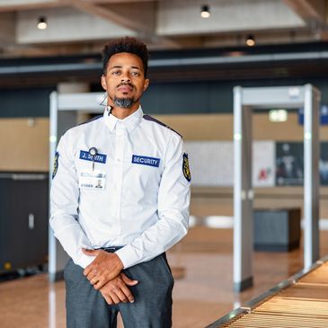 Security officer standing alert at a checkpoint in a modern building.
