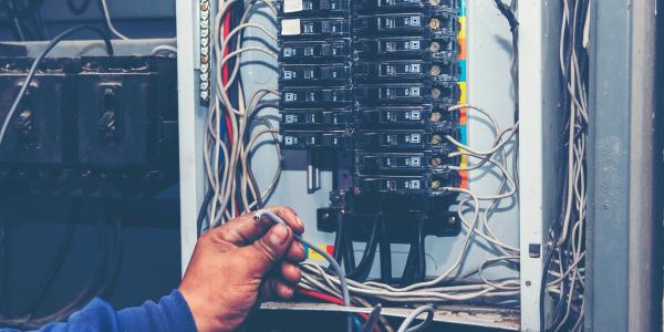 Electrician working on circuit breaker panel wiring.