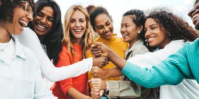 A diverse group of happy women joining hands in a circle.