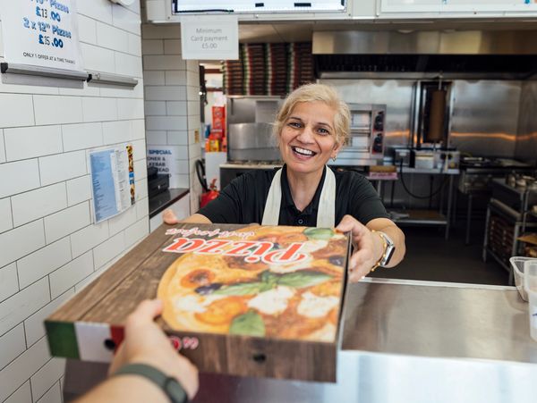 Smiling woman handing over a pizza box.