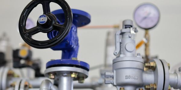 Close-up of industrial valve with pressure gauge in background.