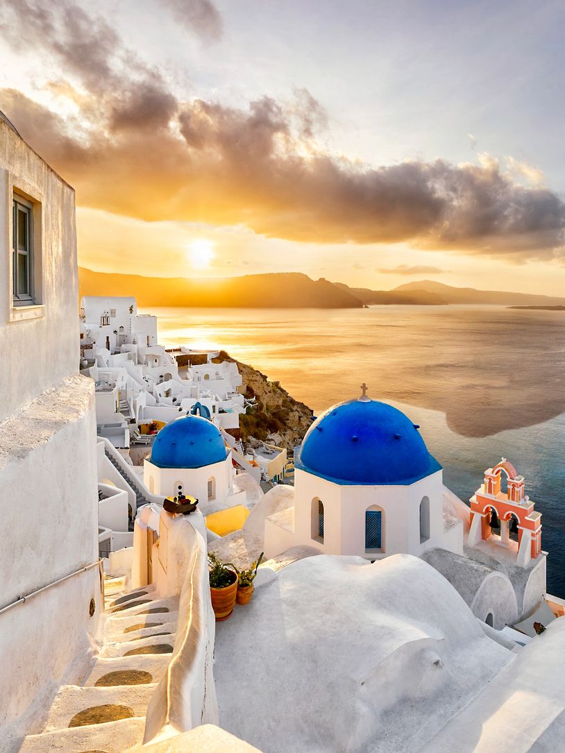 Sunset over Santorini with iconic white buildings and blue domes.