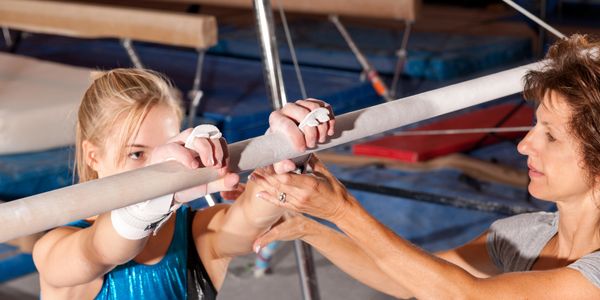 Gymnast receiving coaching on uneven bars.