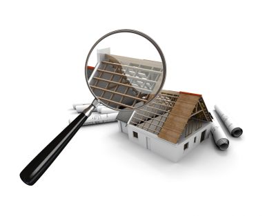 Magnifying glass inspecting a house model with blueprints.