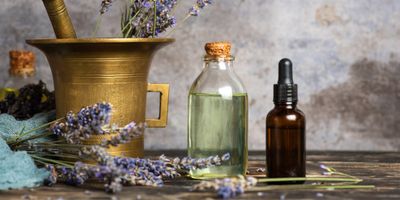 Essential oils and dried lavender with a brass mortar.