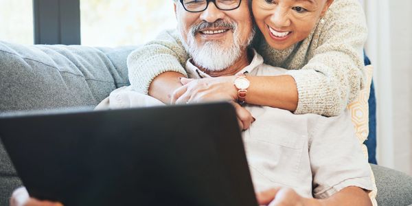 Smiling elderly couple enjoying time together with a laptop.
