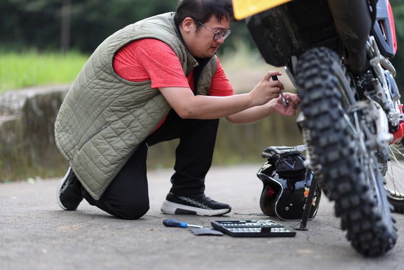 One man is troubleshooting a motorcycle problem while on a motorcycle camping trip