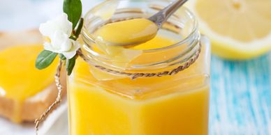 Spoonful of lemon curd over a jar.