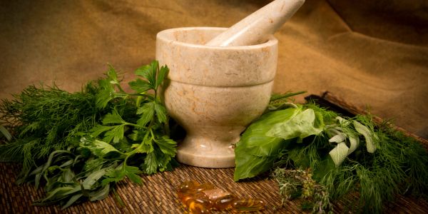 Marble mortar and pestle with fresh herbs.
