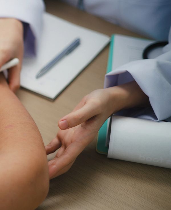 A doctor checking a patient's pulse during a consultation.