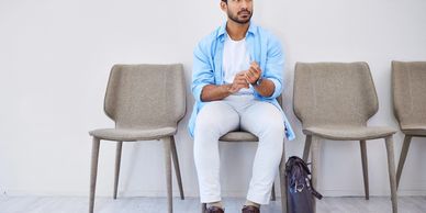 Man waiting nervously in a row of empty chairs.