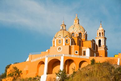 Iglesia colonial amarilla en una colina bajo un cielo despejado.