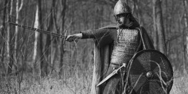 Medieval warrior with sword and shield in forest.