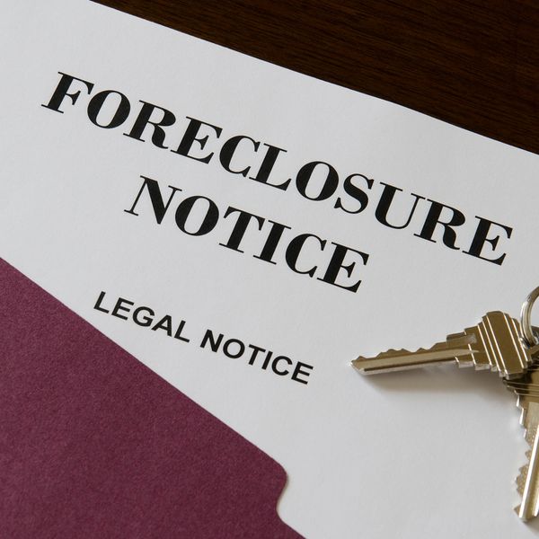 A foreclosure notice document with keys and a folder on a wooden surface.