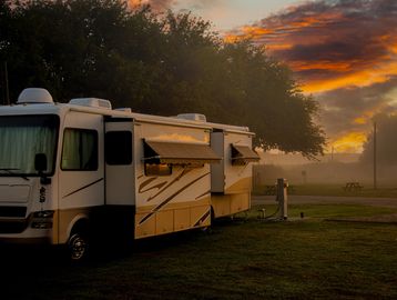 RV parked at sunset with a glowing sky.