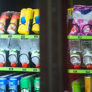 Vending machine stocked with water bottles, snack packs, and soda cans.