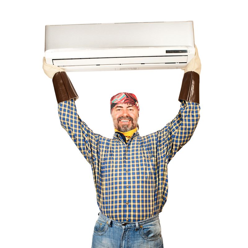Air conditioning master holding in his arms new air conditioner and smiling. Isolated on a white