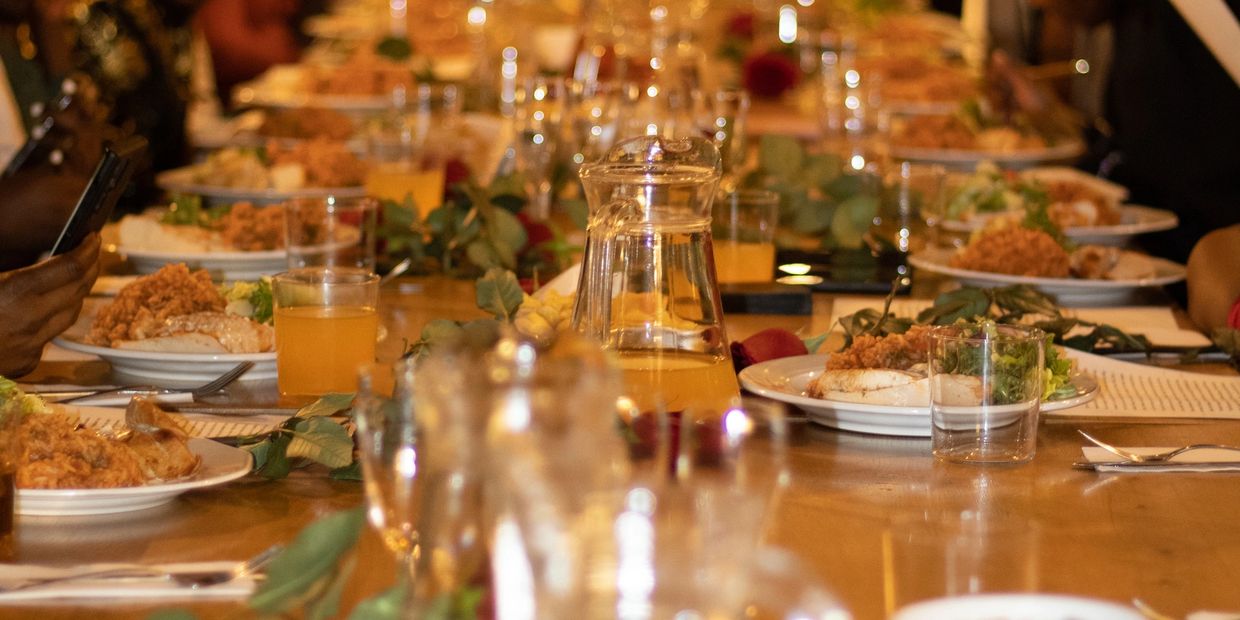 A long dining table set for a meal with people eating and drinking.