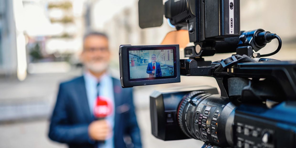 News reporter filming a live broadcast with a professional camera.