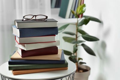 A stack of books and a pair of glasses on a table. 