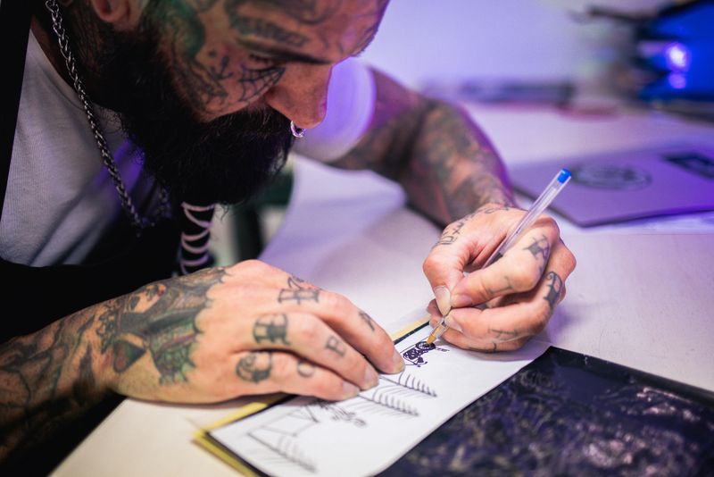 Tattoo artist working at his studio and drawing a sketch of the tattoo he's going to make.