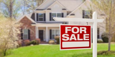 A house with a red and white 'For Sale' sign in the front yard.