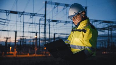 Engineer inspecting electrical grid at dusk.